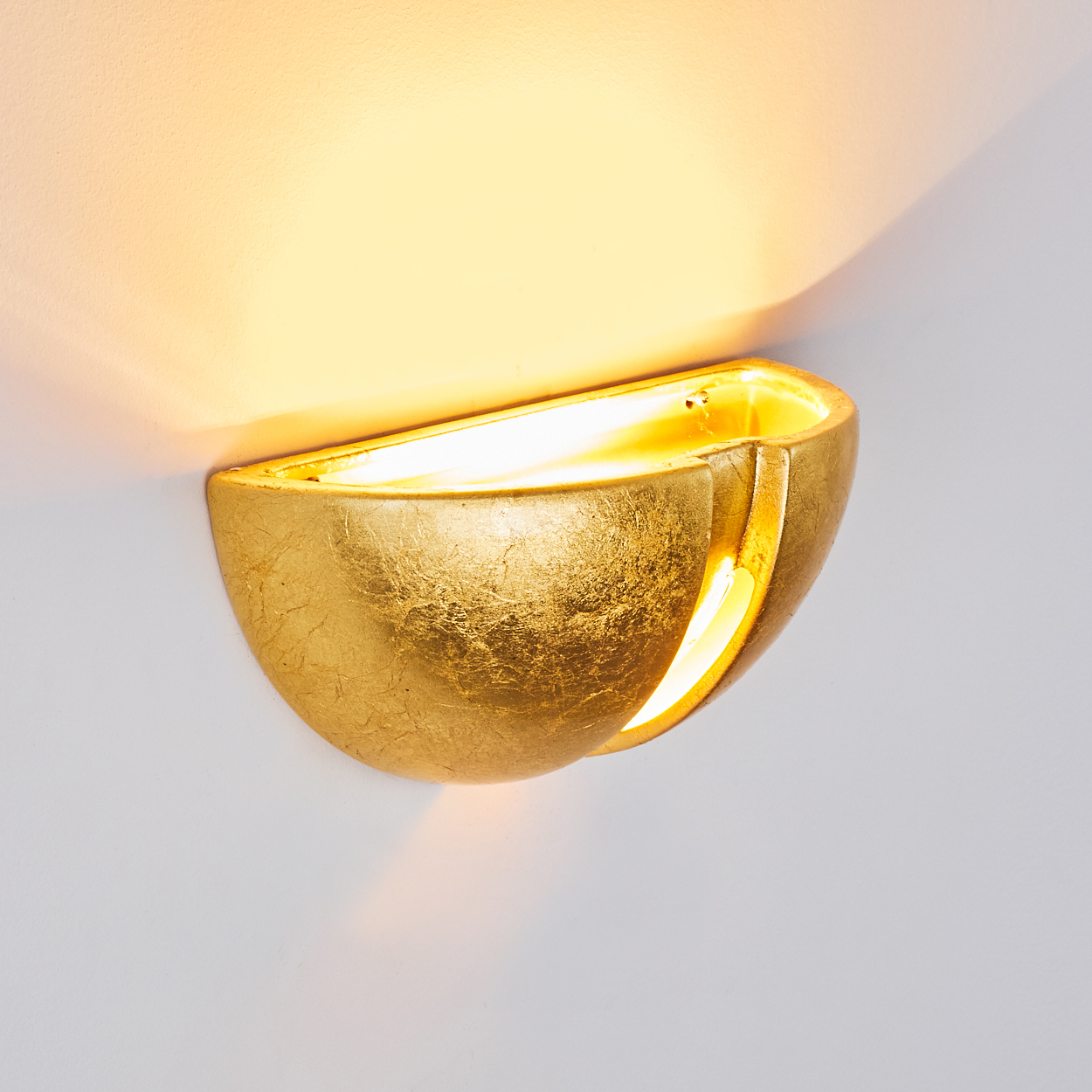 Goldene Wandleuchte wirft warmes Licht an die Wand.