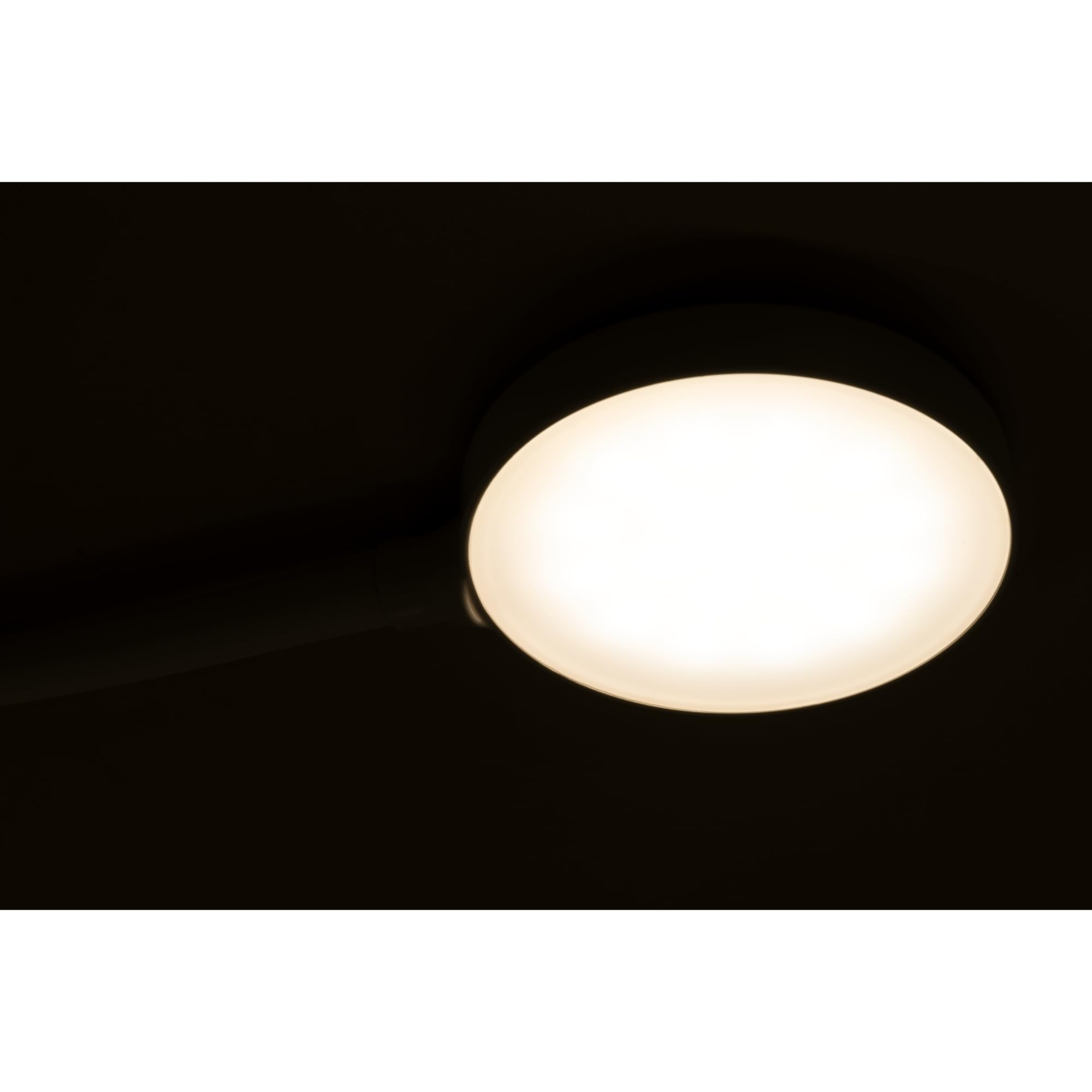 Eine runde weiße Lampe leuchtet hell auf dunklem Hintergrund.
