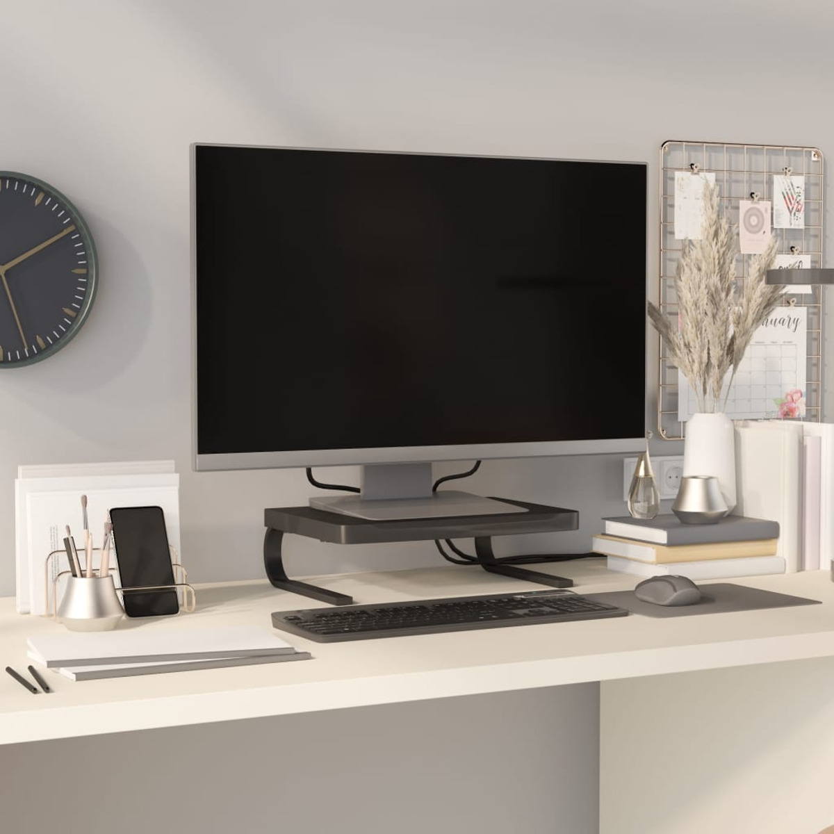 Ein Schreibtisch mit Monitor, Tastatur, Maus, Uhr und Bürobedarf.
