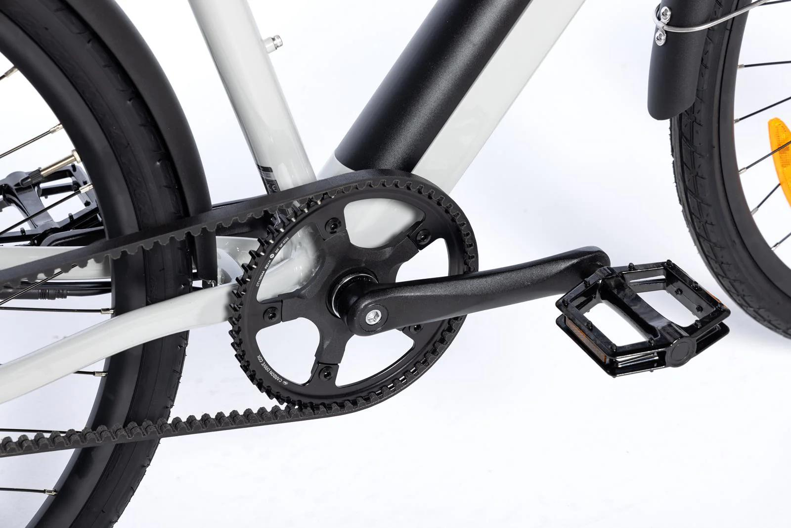 Primo piano di pedivella bicicletta con cinghia nera, pedale e telaio bianco.