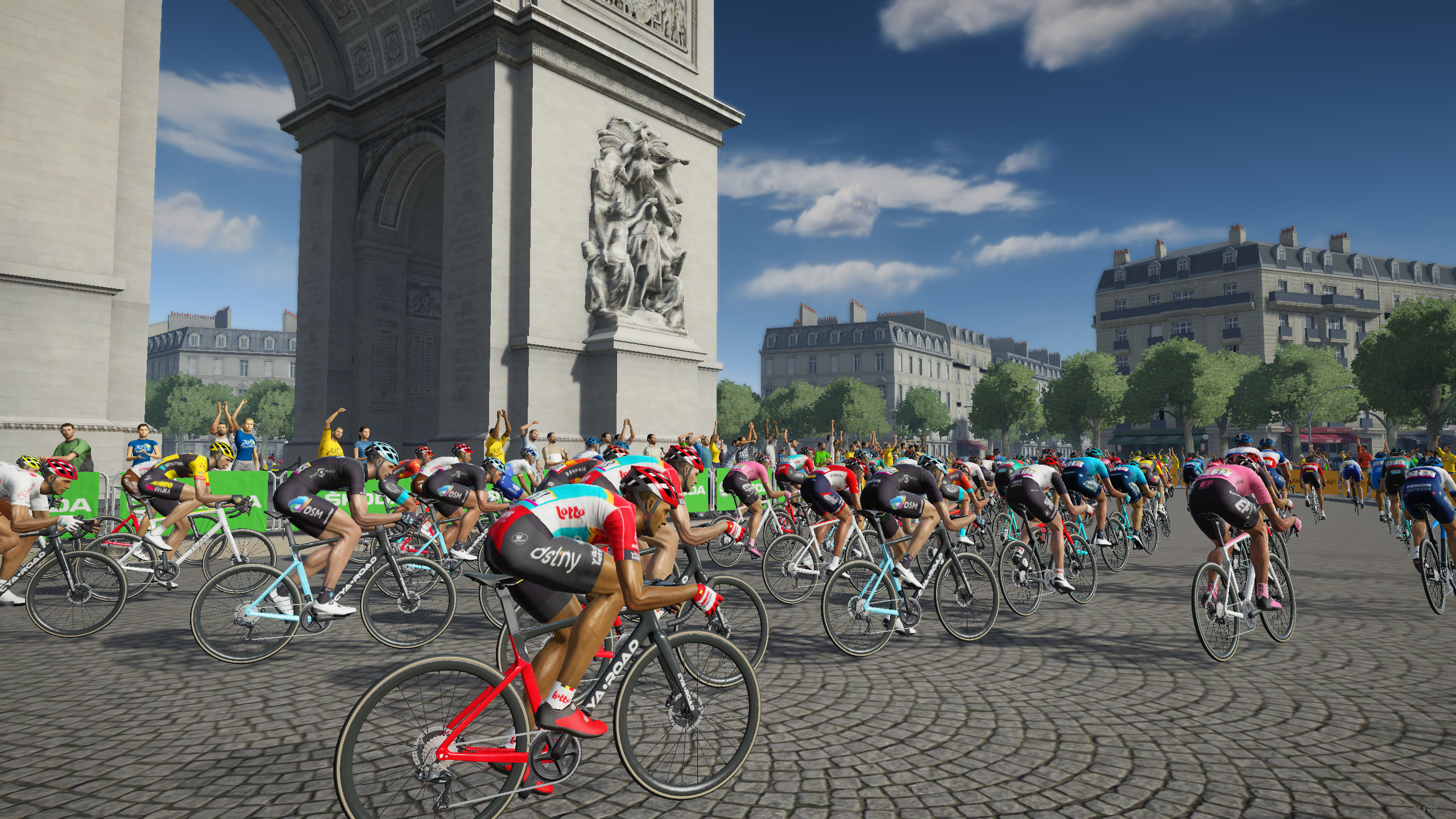 Radsportler fahren auf einer Kopfsteinpflasterstraße vor dem Arc de Triomphe.