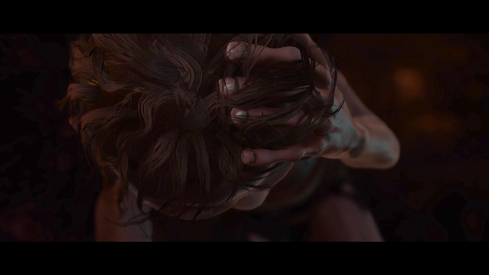 Eine Nahaufnahme einer Person, die sich die Haare greift, mit dunklem Hintergrund.