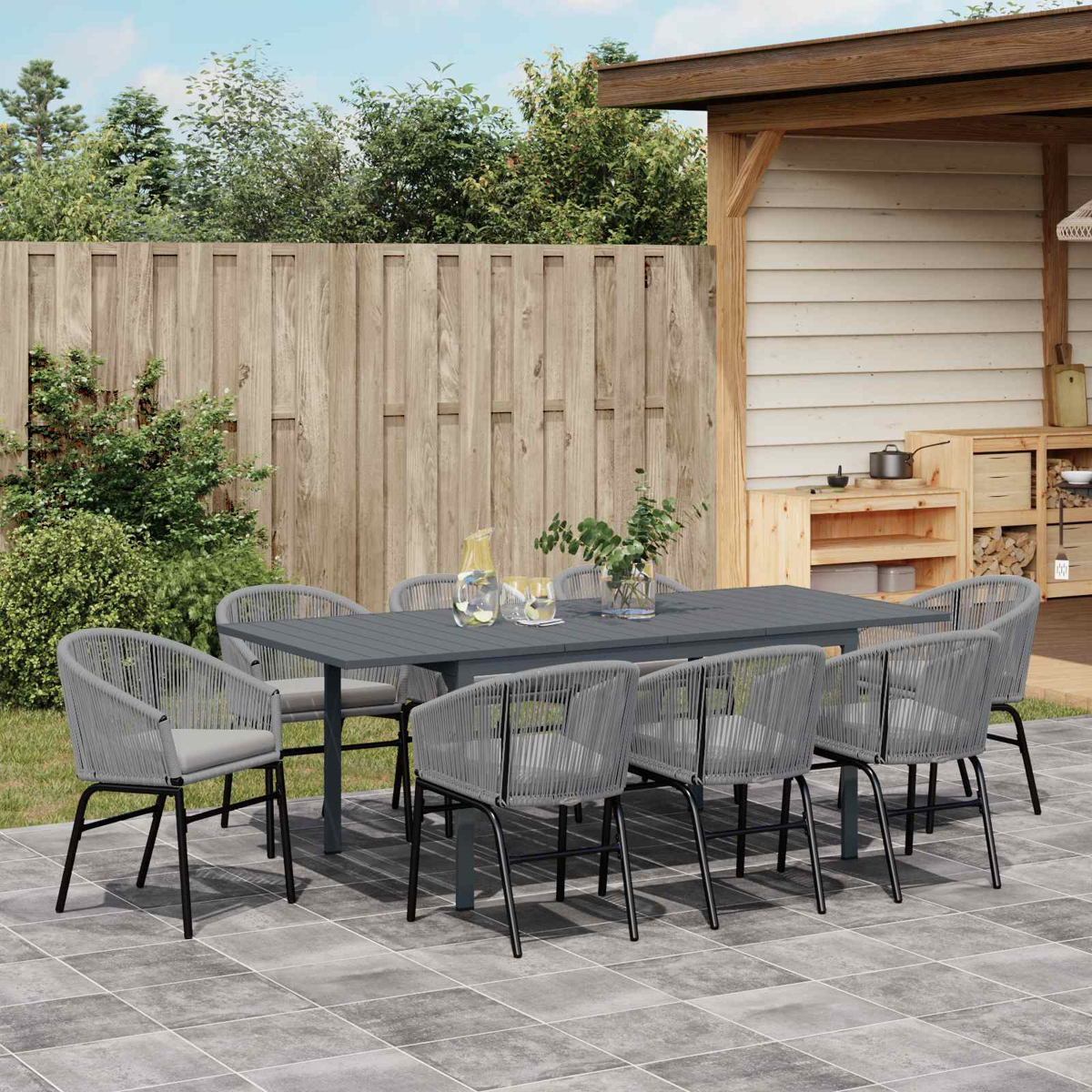 Ein graues Gartenmöbelset mit Tisch und acht Stühlen auf einer gefliesten Terrasse.