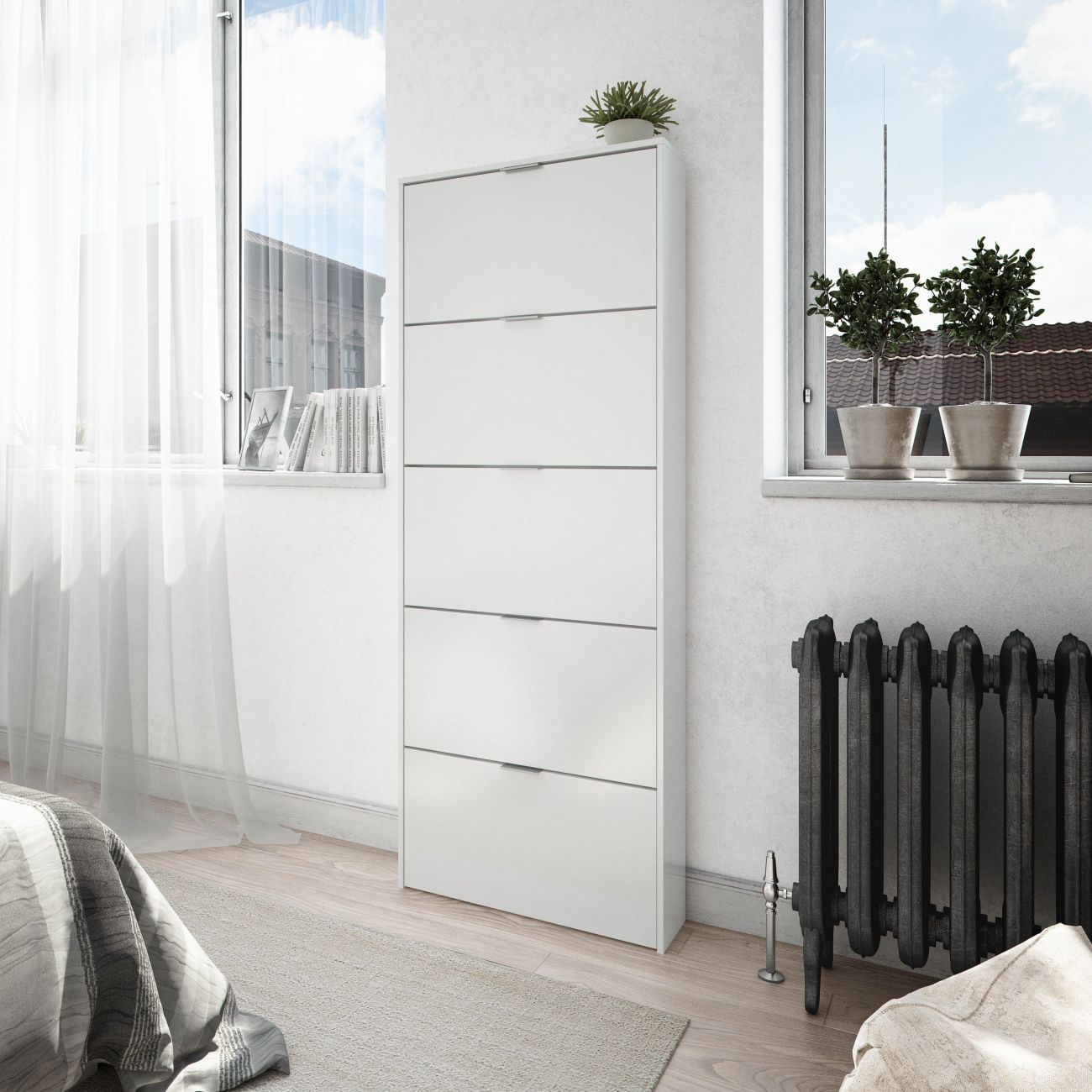 Un mueble blanco con cinco cajones está junto a una ventana con plantas.