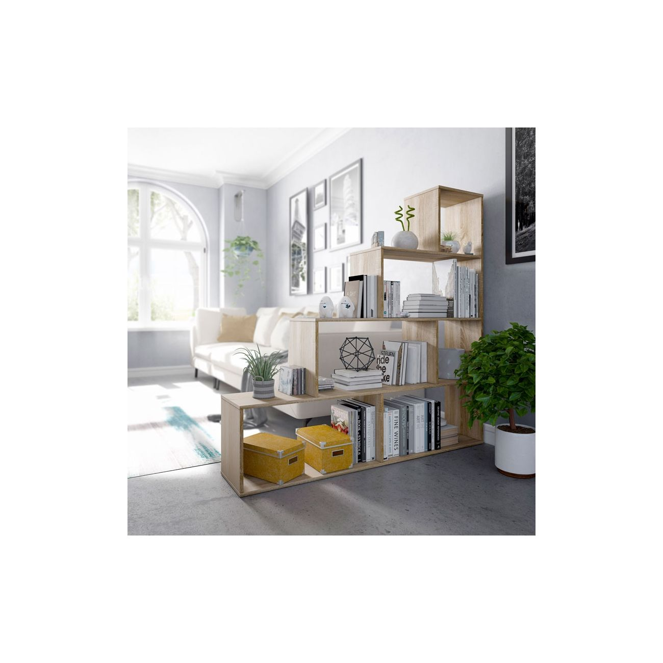 Una estantería con libros, plantas y decoración frente a un sofá luminoso.