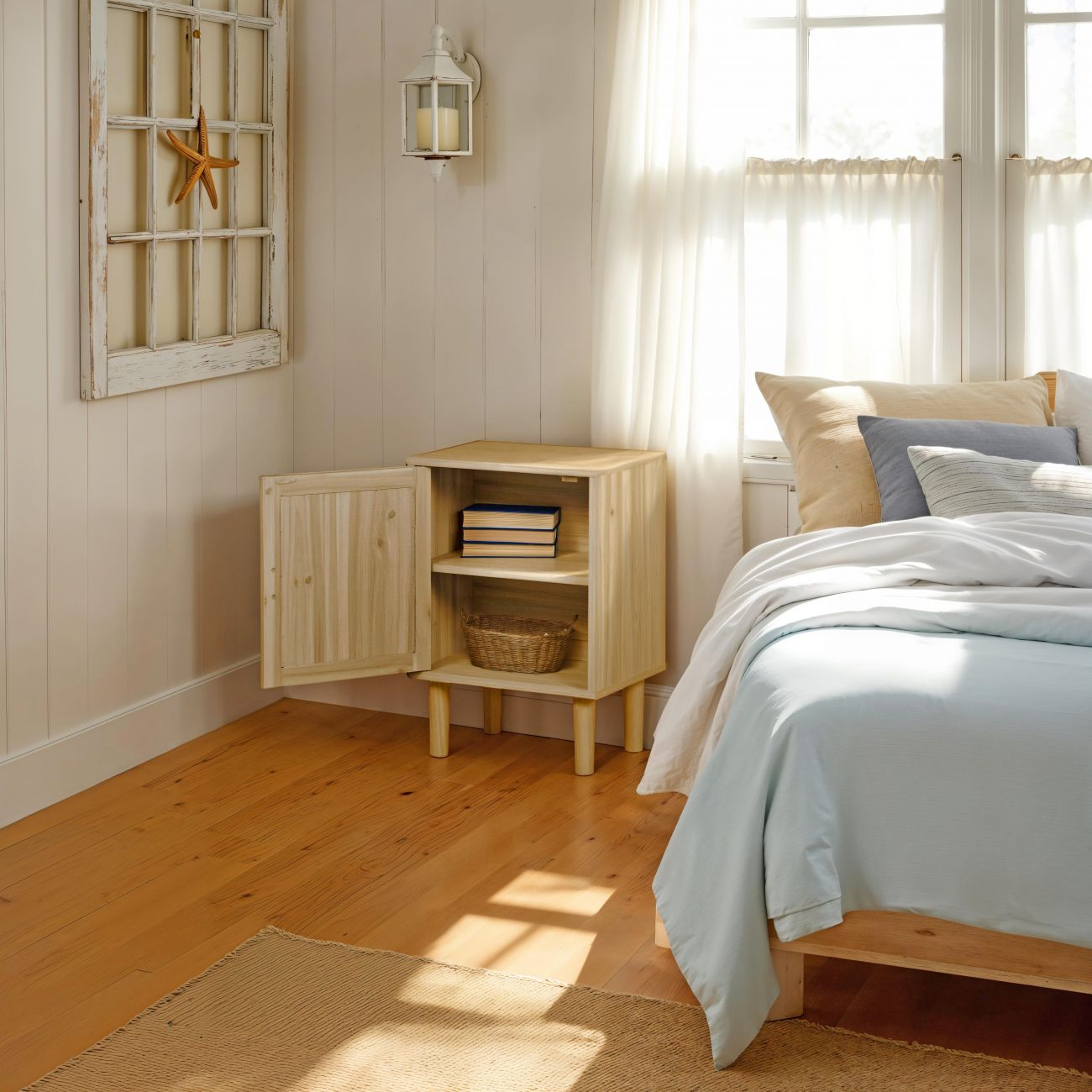 Armario de madera junto a la cama con libros y cesta. Ventana decorativa con estrella de mar.