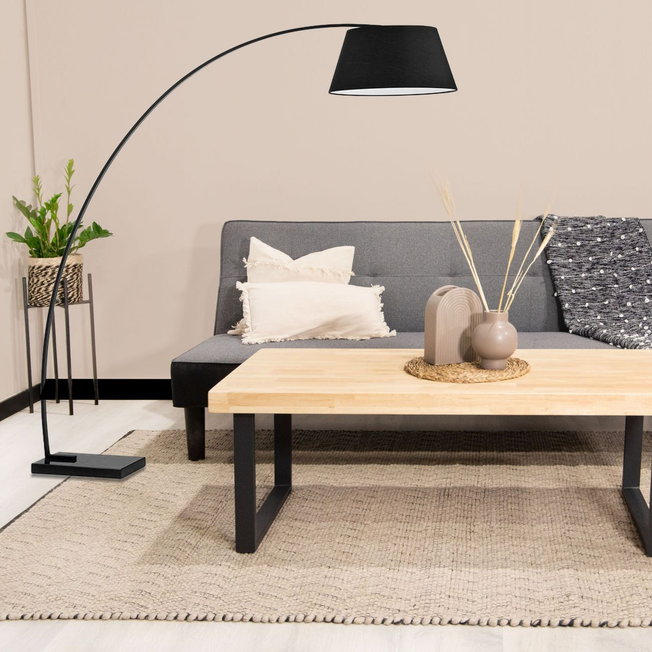 Una sala de estar con sofá, mesa de centro, lámpara y planta.