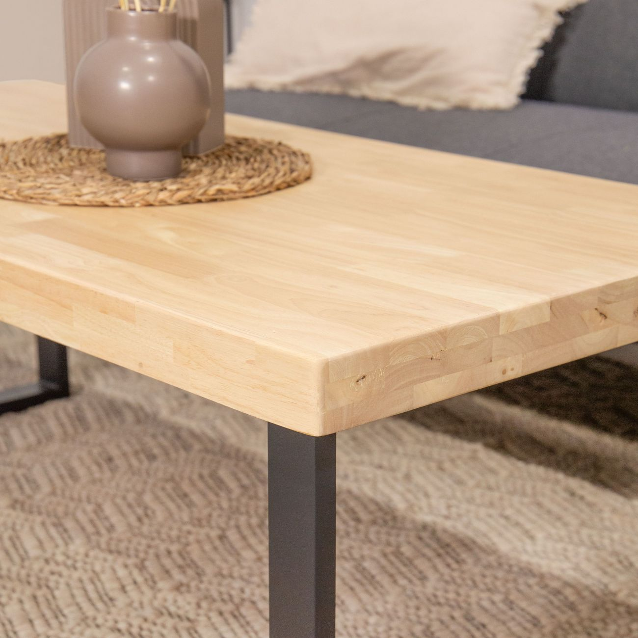 Una mesa de centro de madera con patas de metal oscuro está sobre una alfombra.