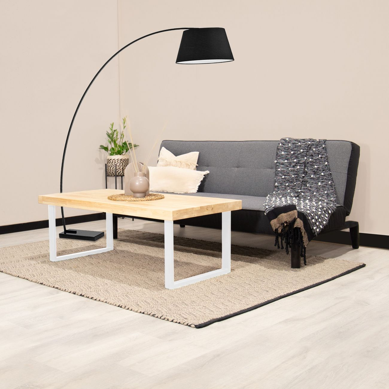 Una sala de estar moderna con sofá gris, mesa de centro de madera y lámpara de pie.