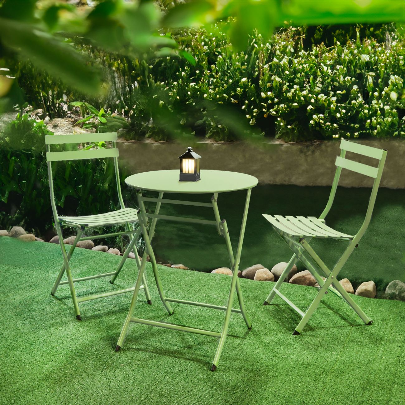 Una mesa de jardín verde con dos sillas y una linterna.