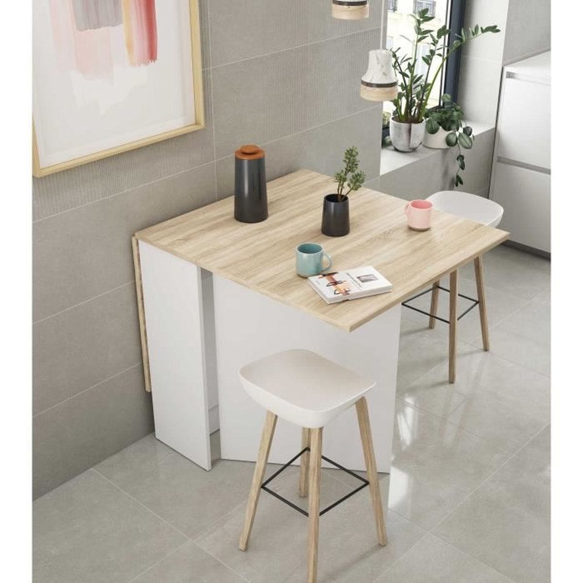 Una mesa pequeña de madera con taburetes blancos y decoración cerca de una ventana.