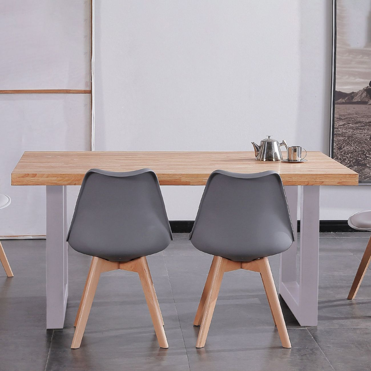Dos sillas grises con patas de madera delante de una mesa de madera con tetera.
