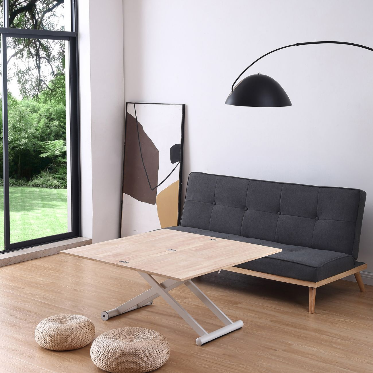 Una sala de estar luminosa con mesa de madera, sofá, dos taburetes y un cuadro.