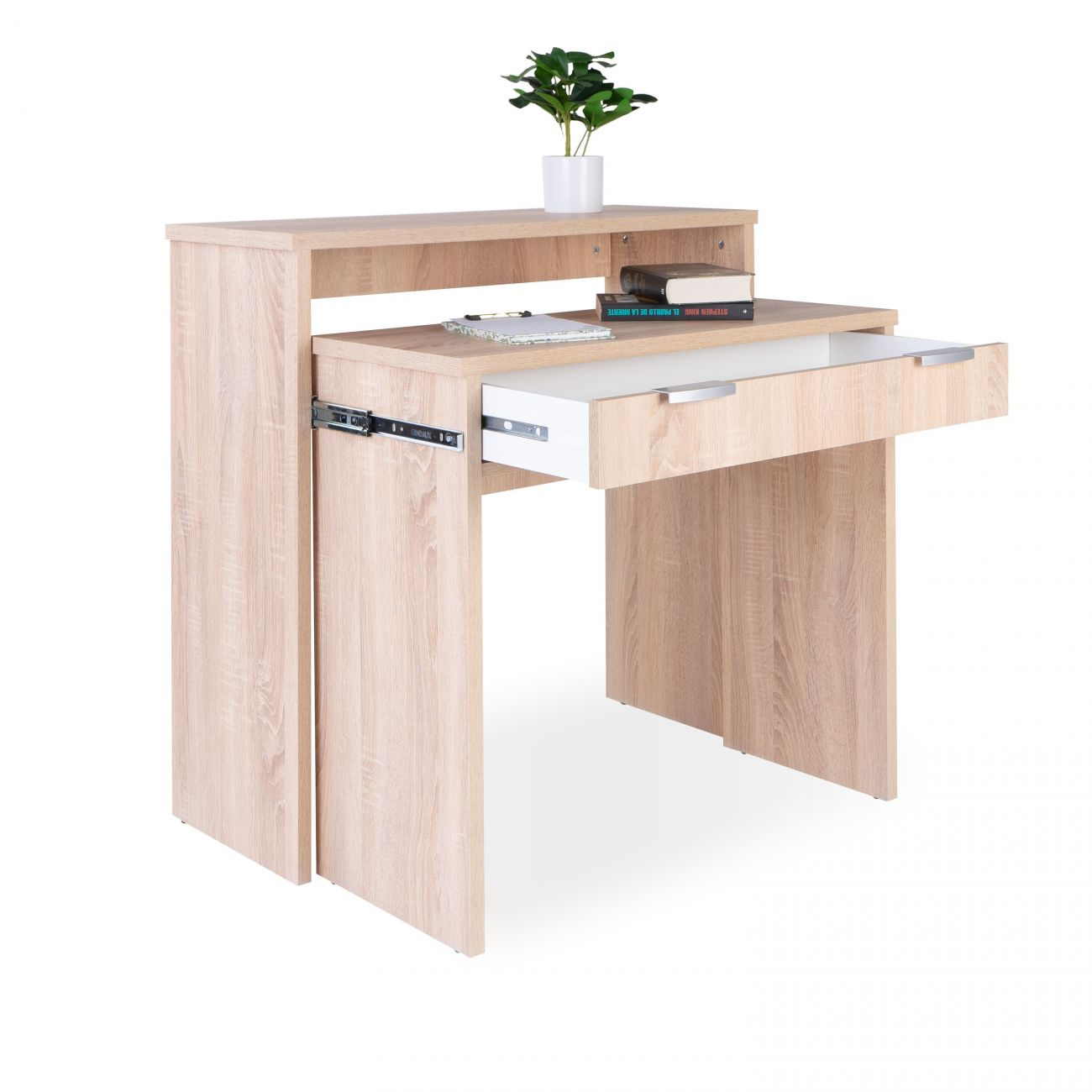 Un escritorio de madera clara con cajón abierto, libros y planta.