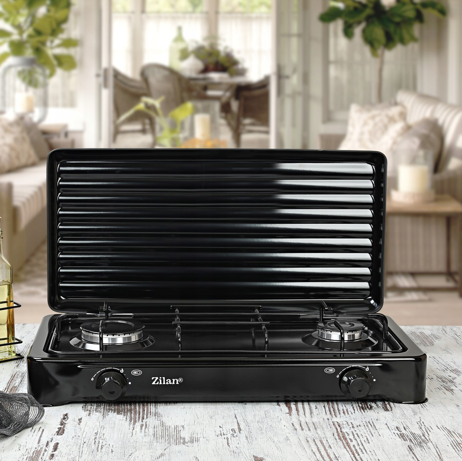 Czarny przenośny grill dwupalnikowy na drewnianym stole.