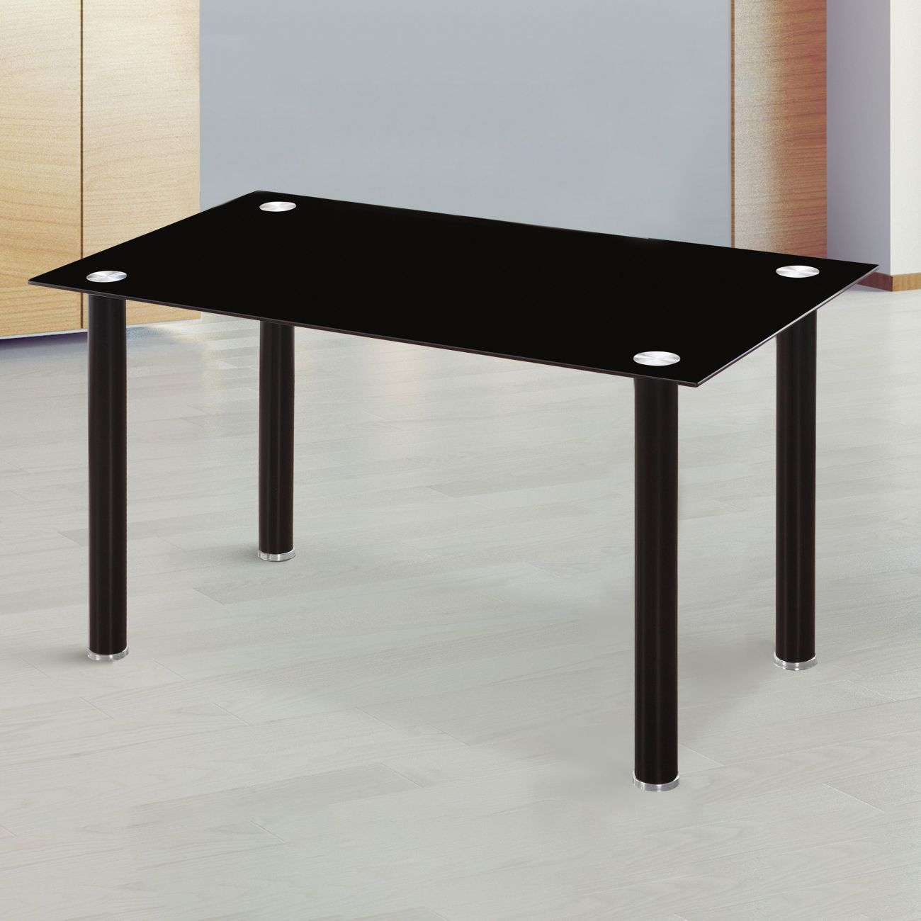 Una mesa de cristal negra con patas oscuras sobre suelo de madera claro.