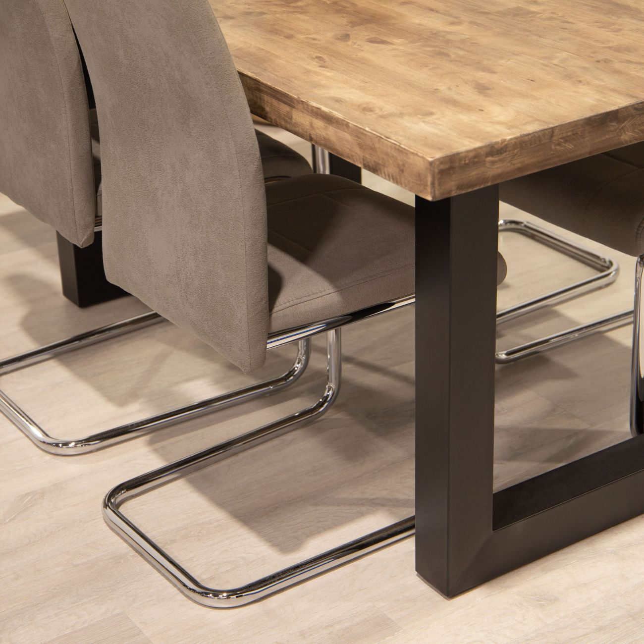 Una mesa de madera con patas negras y sillas grises con estructura cromada.