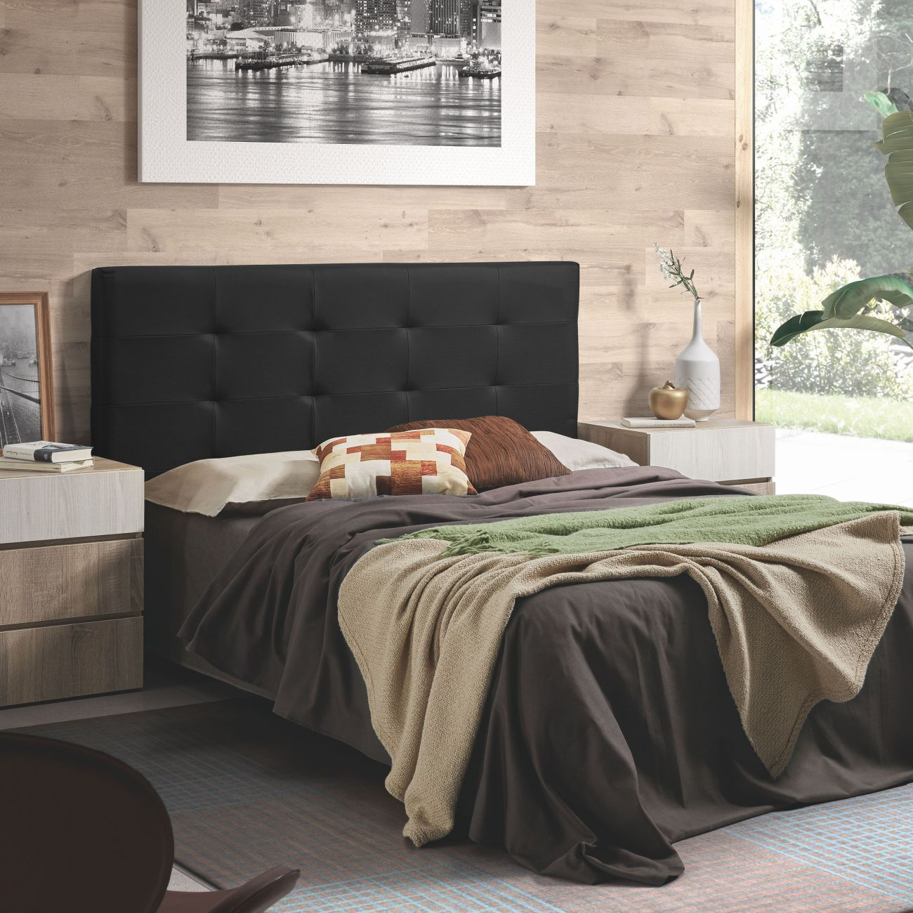 Un dormitorio con cama doble, cabecero negro y dos mesitas de noche.