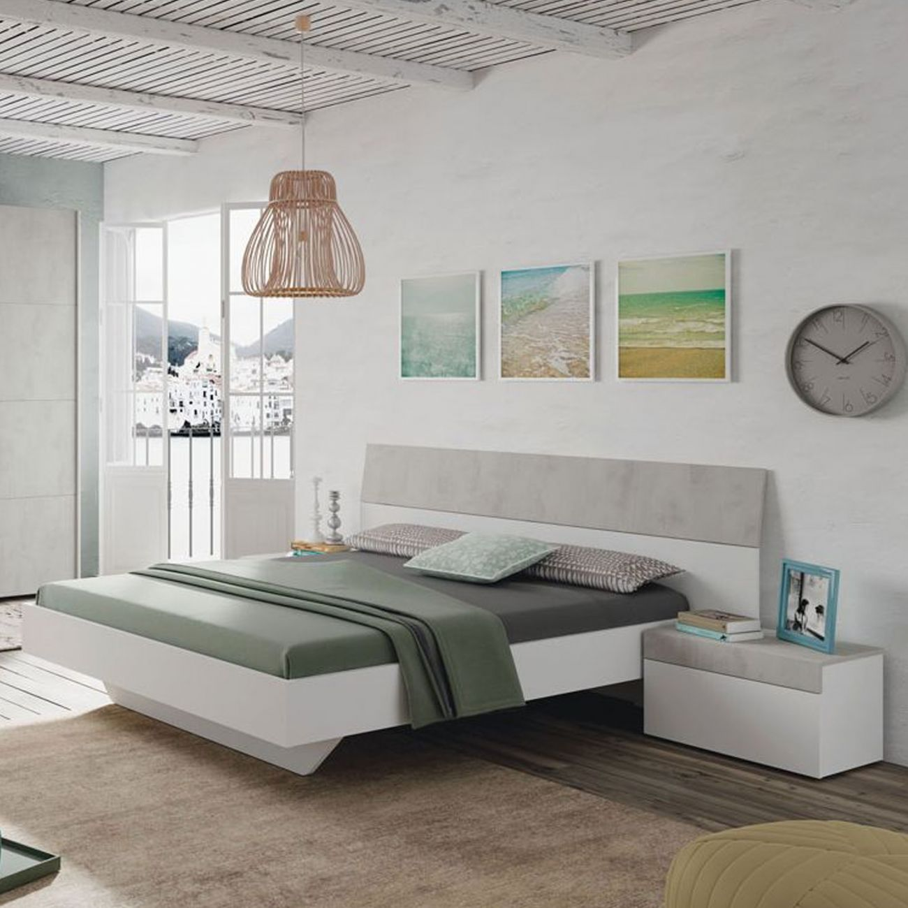 Dormitorio moderno con cama blanca, cabecero gris y vistas al mar.