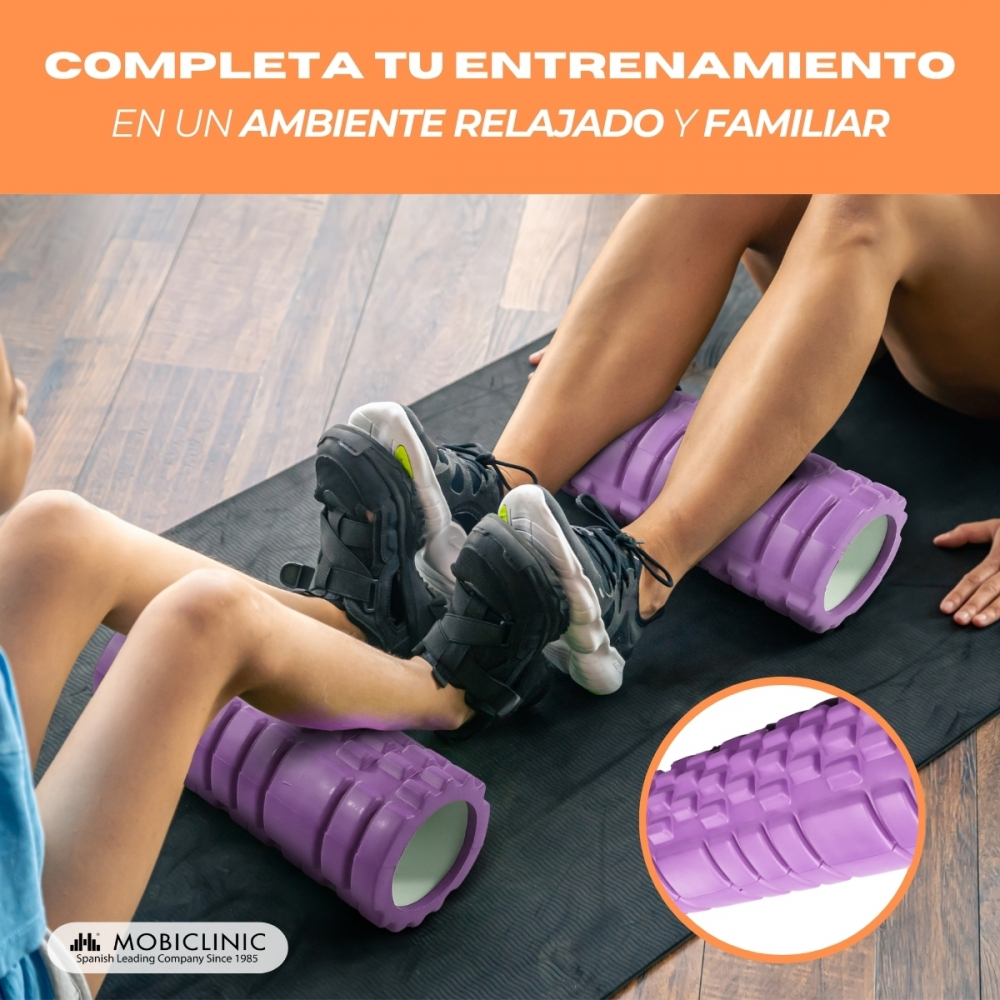Dos personas se enrollan las piernas en rodillos de espuma morados sobre una alfombra.