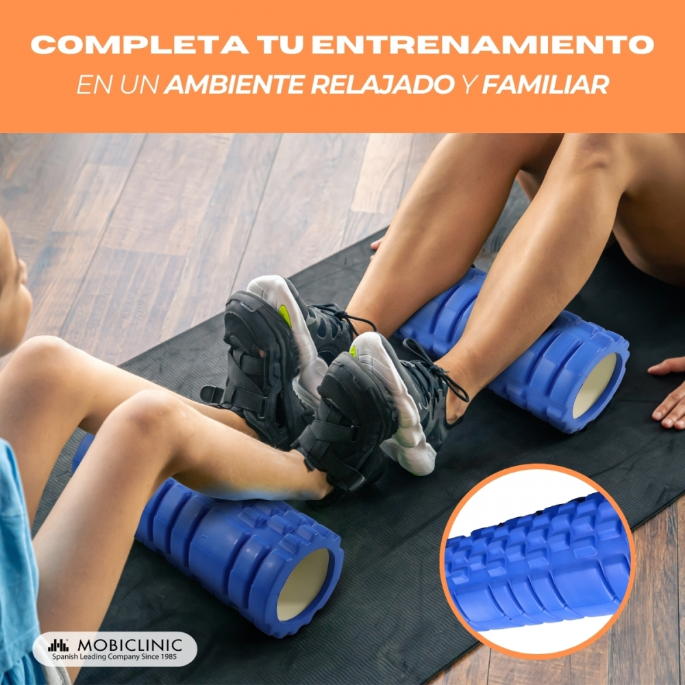 Dos personas usan rodillos de espuma azules para masajear piernas en una esterilla.