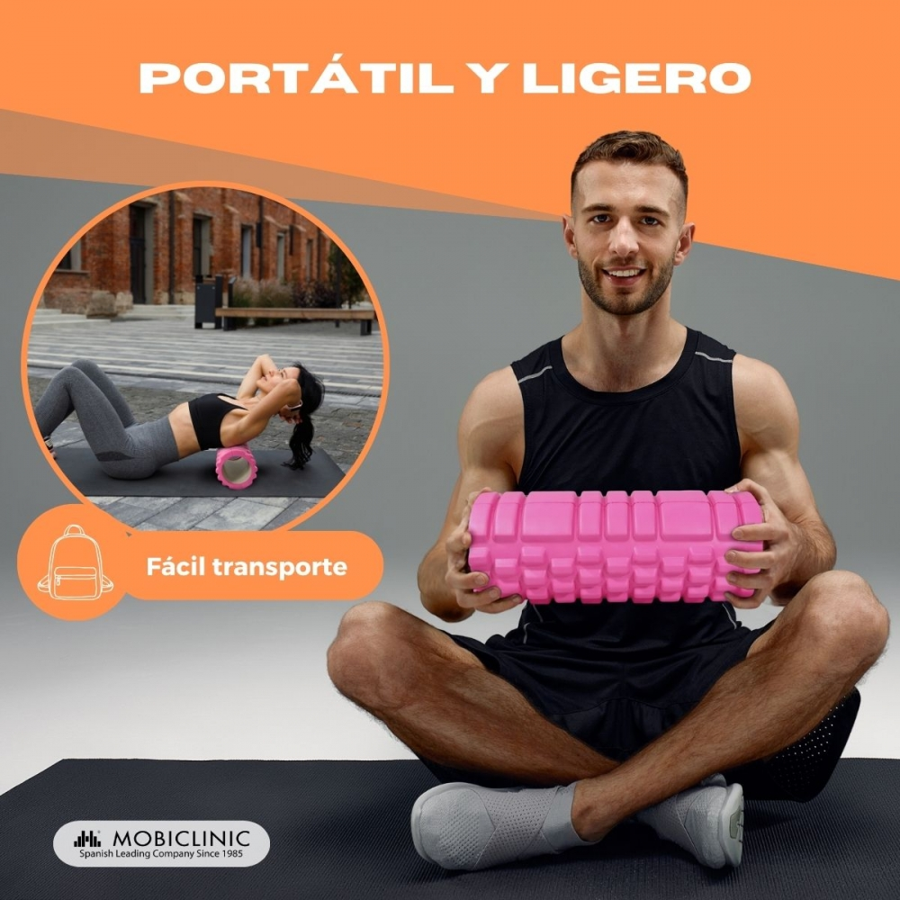 Hombre sostiene rodillo de espuma rosa, mujer entrena al fondo. Portátil.