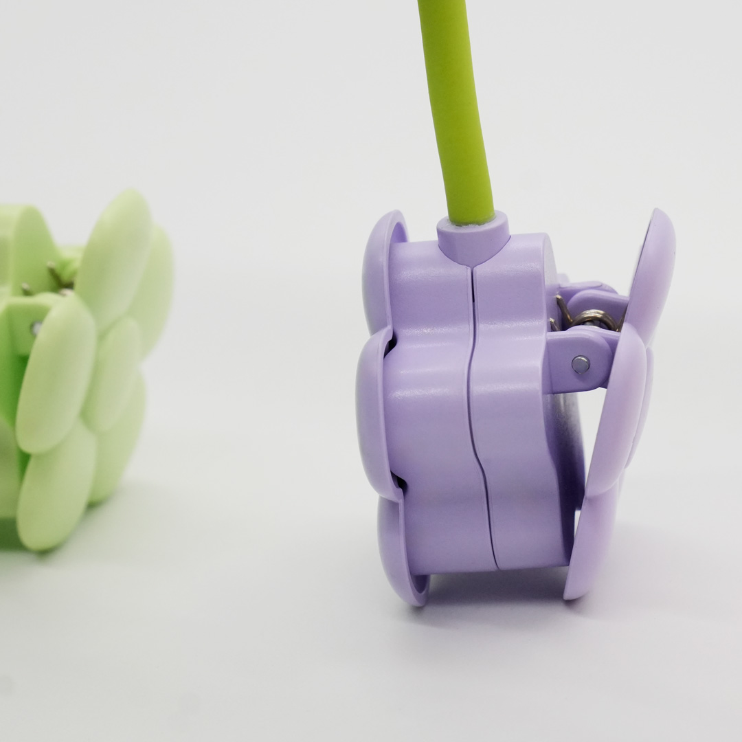 Primo piano di una clip viola con stelo verde e una clip verde chiaro accanto.