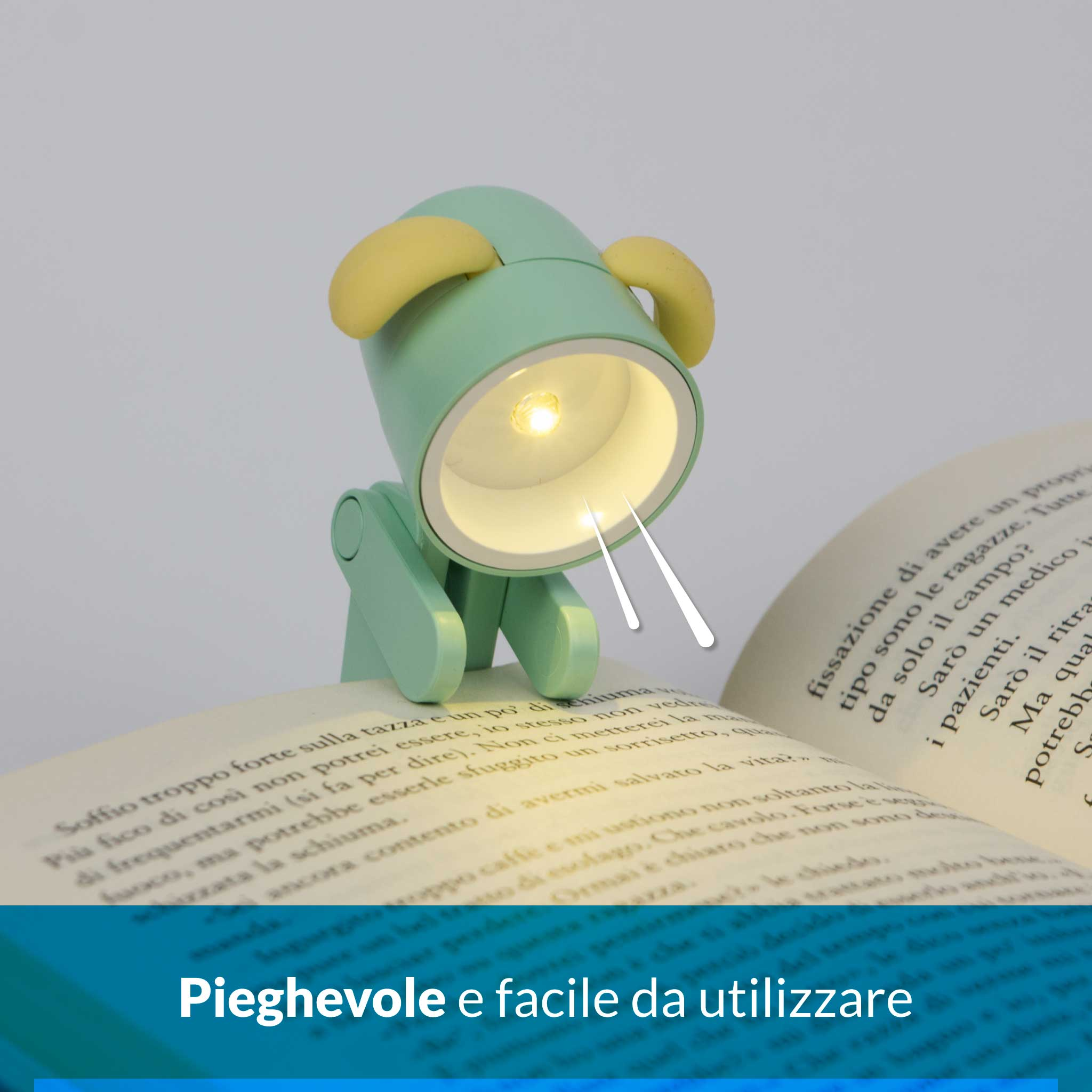 Una luce segnalibro verde a forma di cane con orecchie gialle illumina un libro aperto.