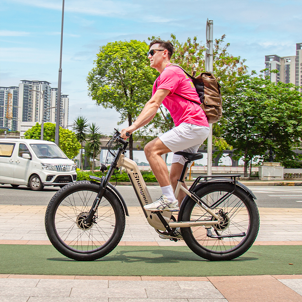 Ein Mann in einem rosafarbenen T-Shirt fährt ein beiges E-Bike auf einem Radweg.