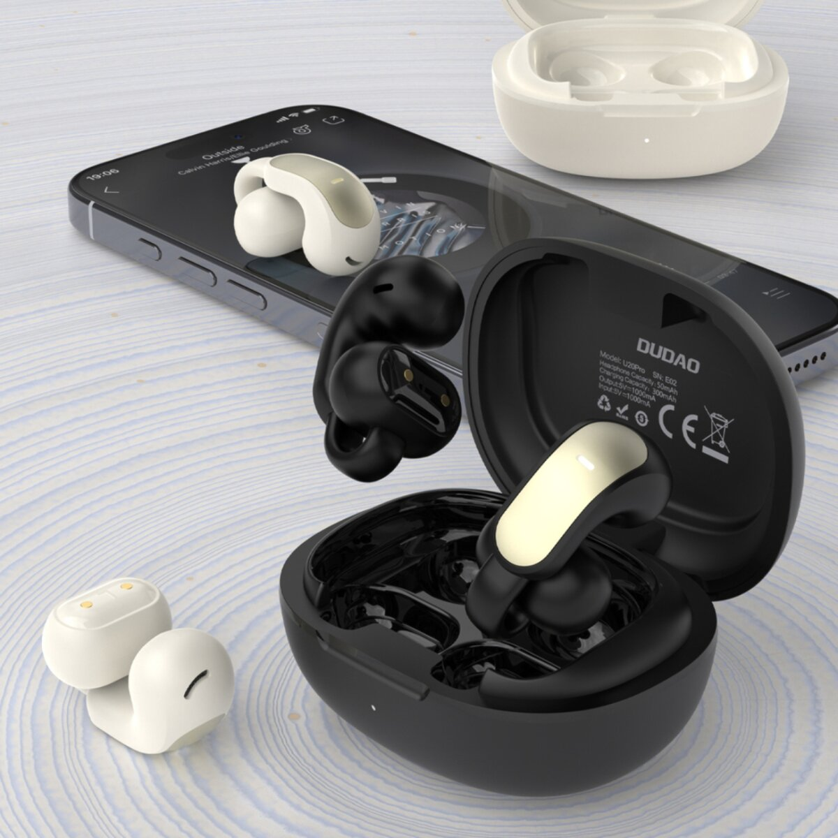 Auricolari bianchi e neri con custodie di ricarica, accanto a uno smartphone.