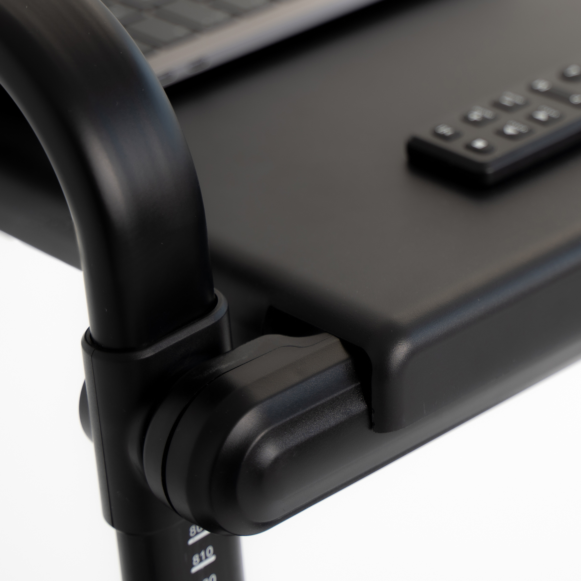 Czarny laptop na czarnym stole z pilotem i mechanizmem regulacji.