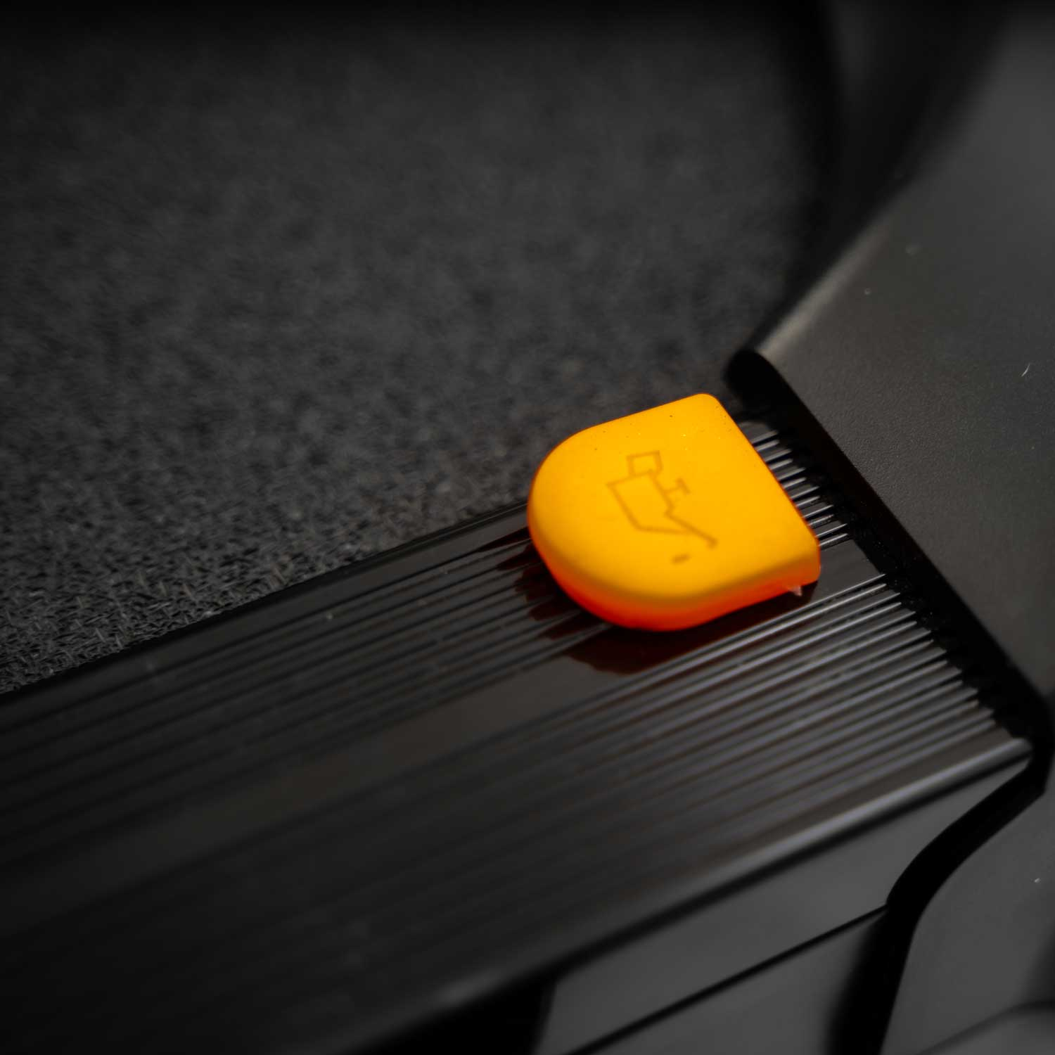 Pomarańczowa wtyczka z logo na czarnym urządzeniu.