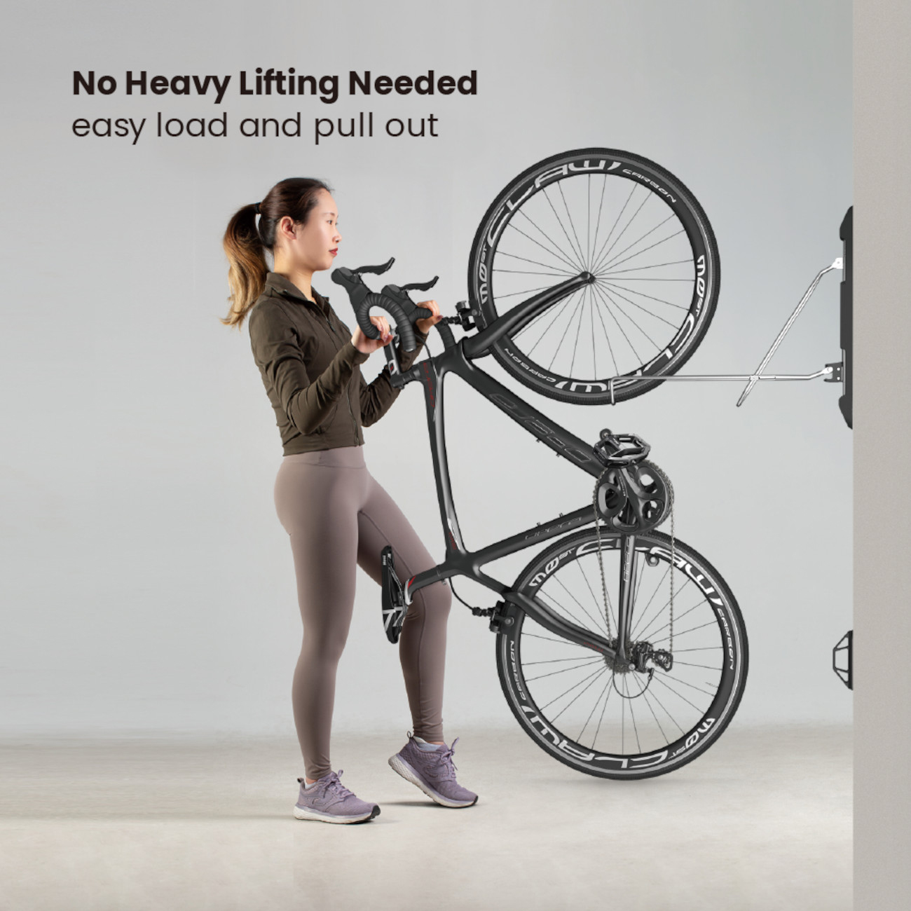 Eine Frau hebt ein Rennrad in eine Wandhalterung.