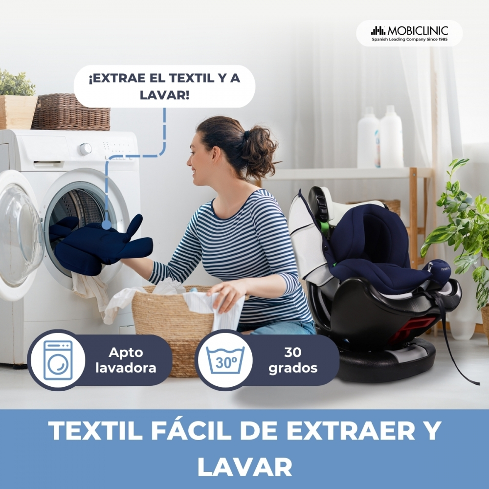 Una mujer saca una funda azul de una lavadora. Hay un asiento infantil al lado.