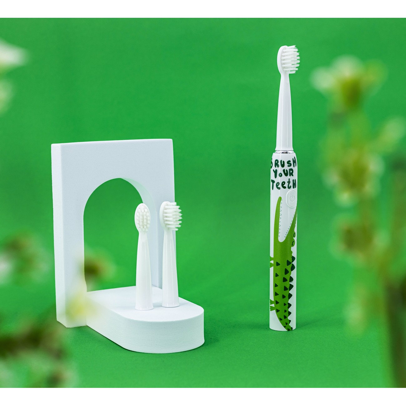 Spazzolino elettrico bianco con design da alligatore su sfondo verde.