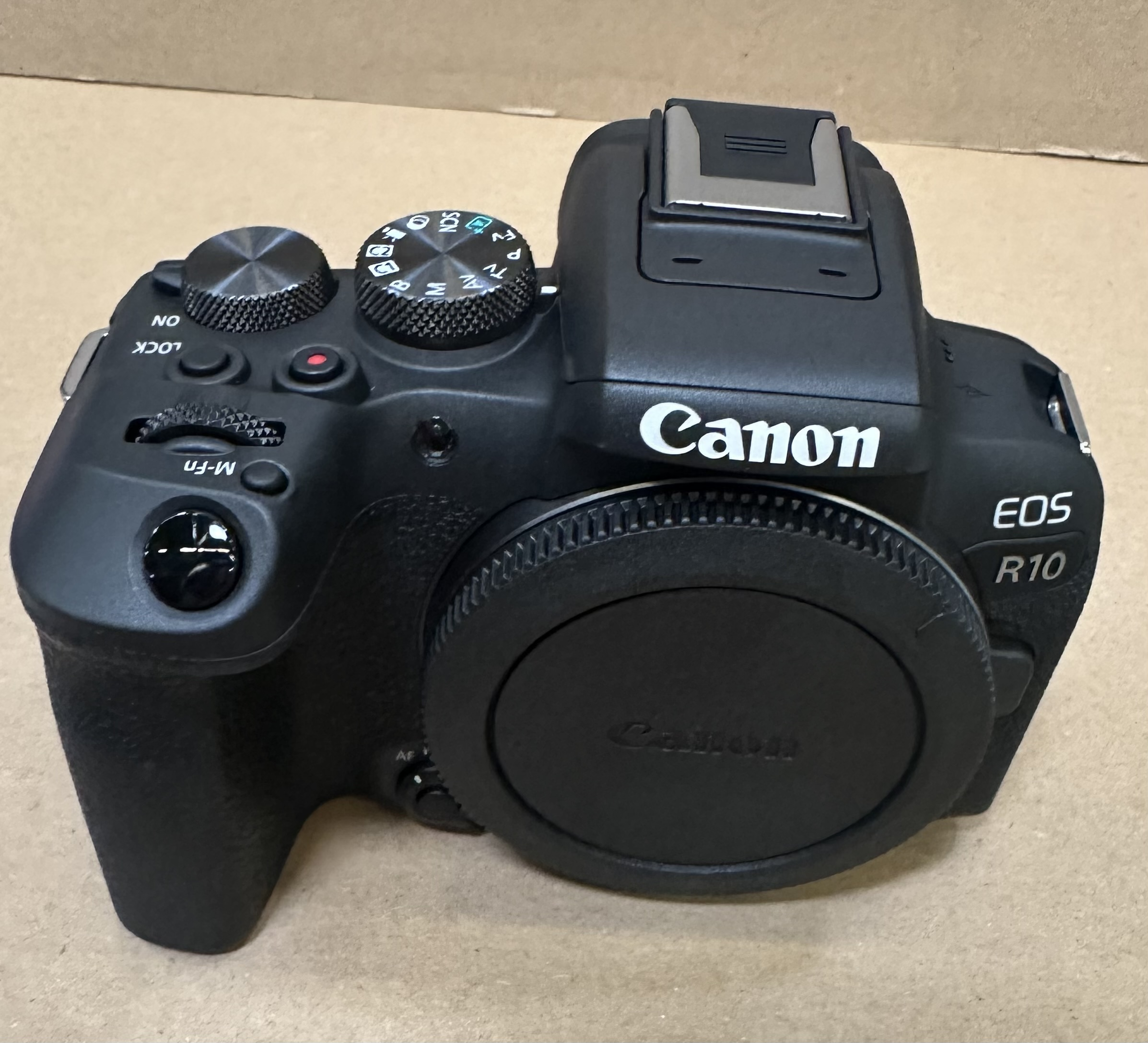 Una fotocamera Canon EOS R10 nera con tappo obiettivo.