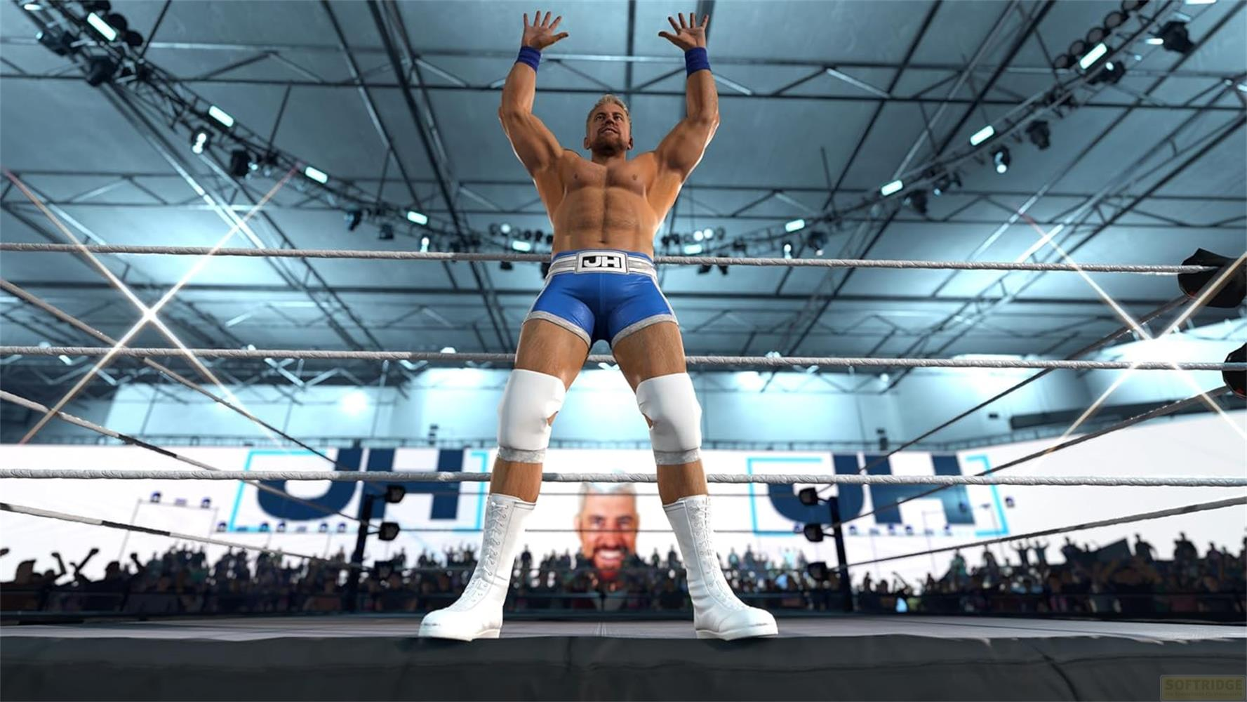 Ein Wrestler mit blauen Hosen steht im Ring und hebt die Arme. Jubelnde Menge im Hintergrund.