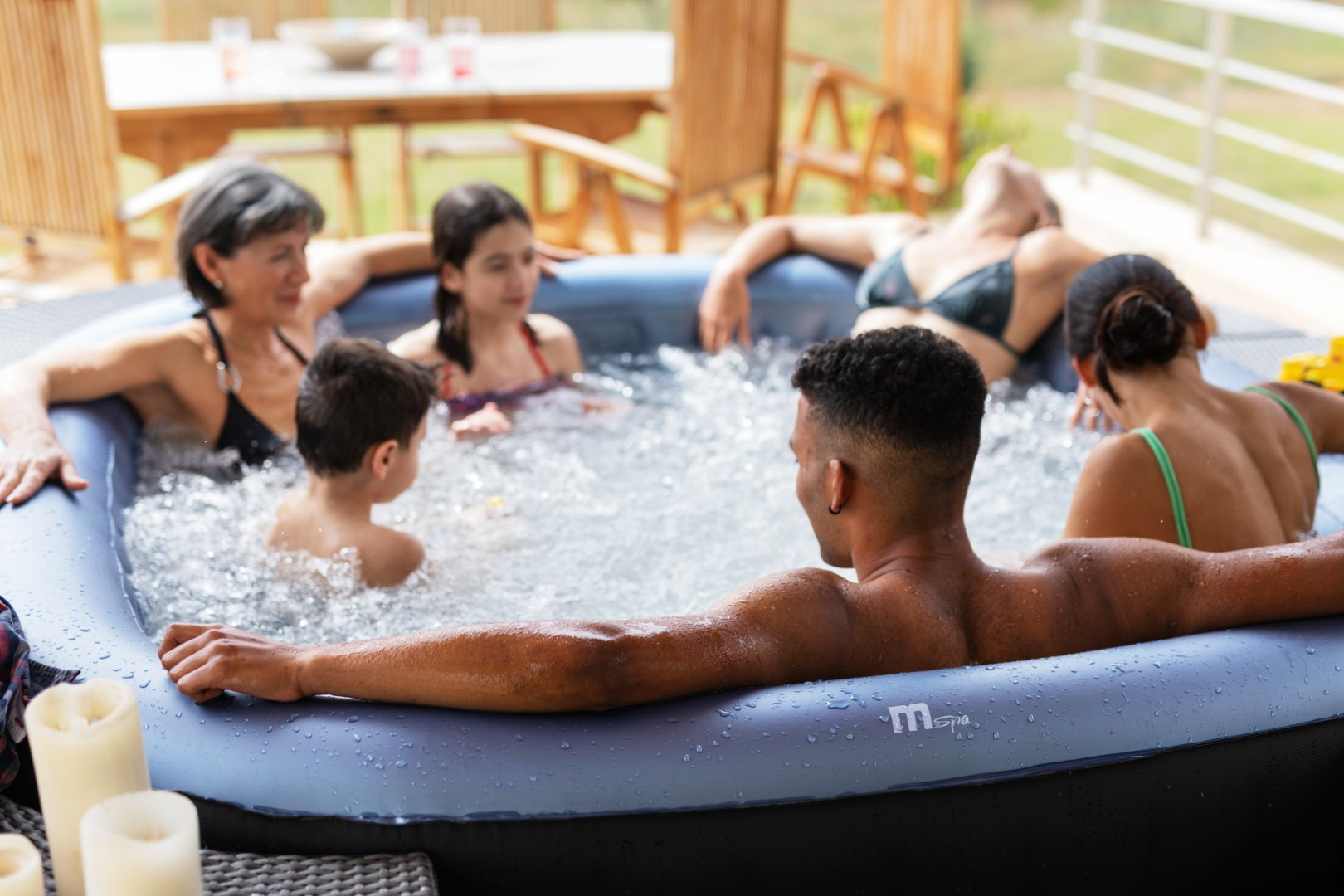 Sechs Personen entspannen sich in einem aufblasbaren Whirlpool im Freien.