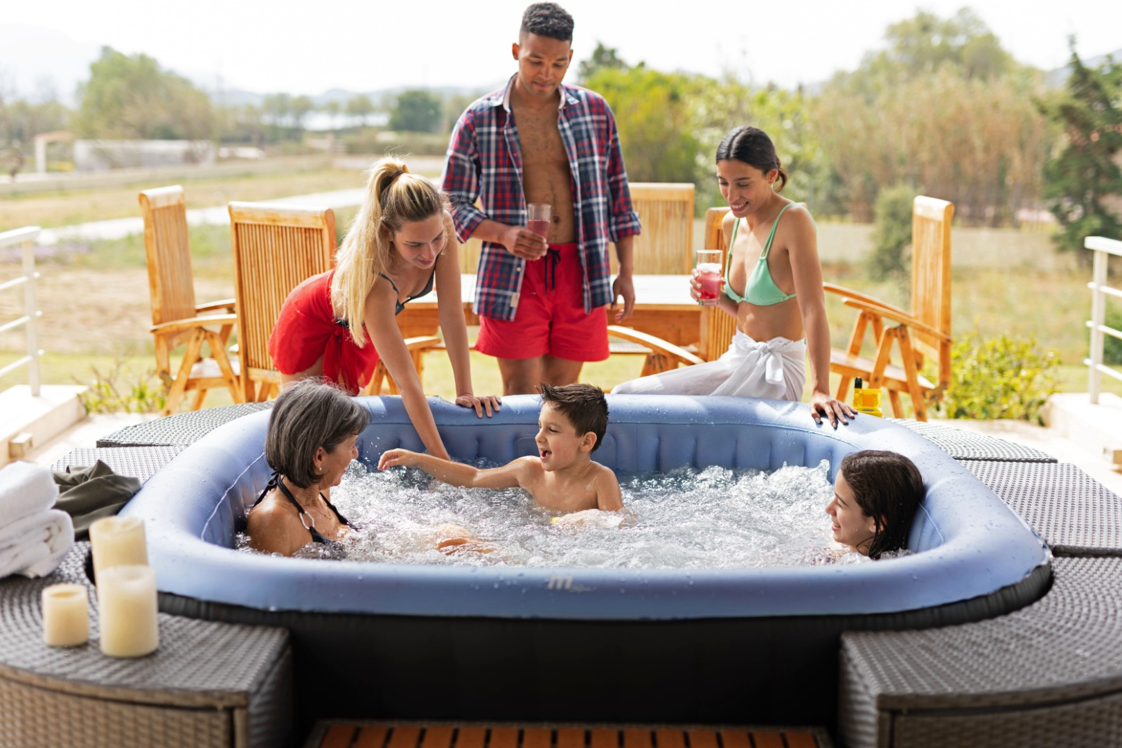 Familie entspannt sich in einem aufblasbaren Whirlpool im Freien bei Sonnenschein.