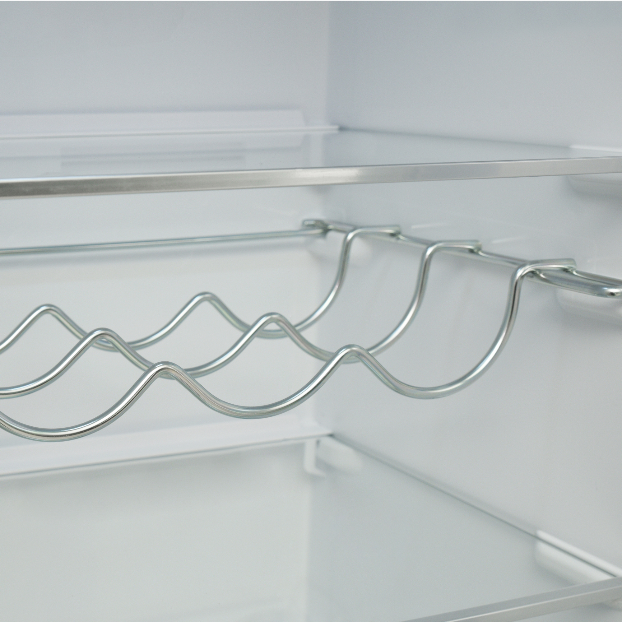 Ein silberner Flaschenhalter mit Wellenmuster in einem weißen Kühlschrank.