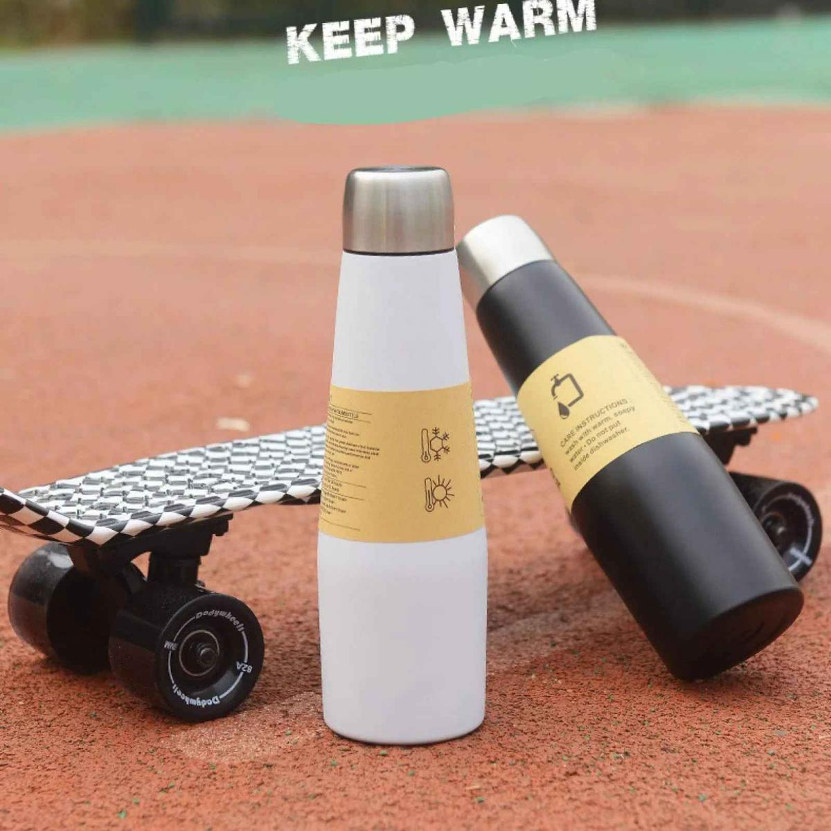 Zwei Thermoskannen und ein Skateboard auf einem roten Untergrund. KEEP WARM.