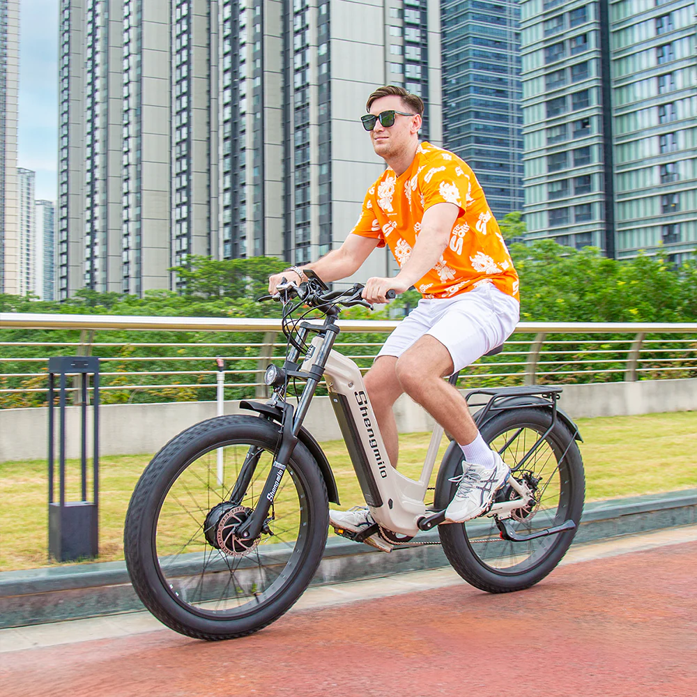 Un uomo guida una e-bike in una città con alti edifici sullo sfondo.