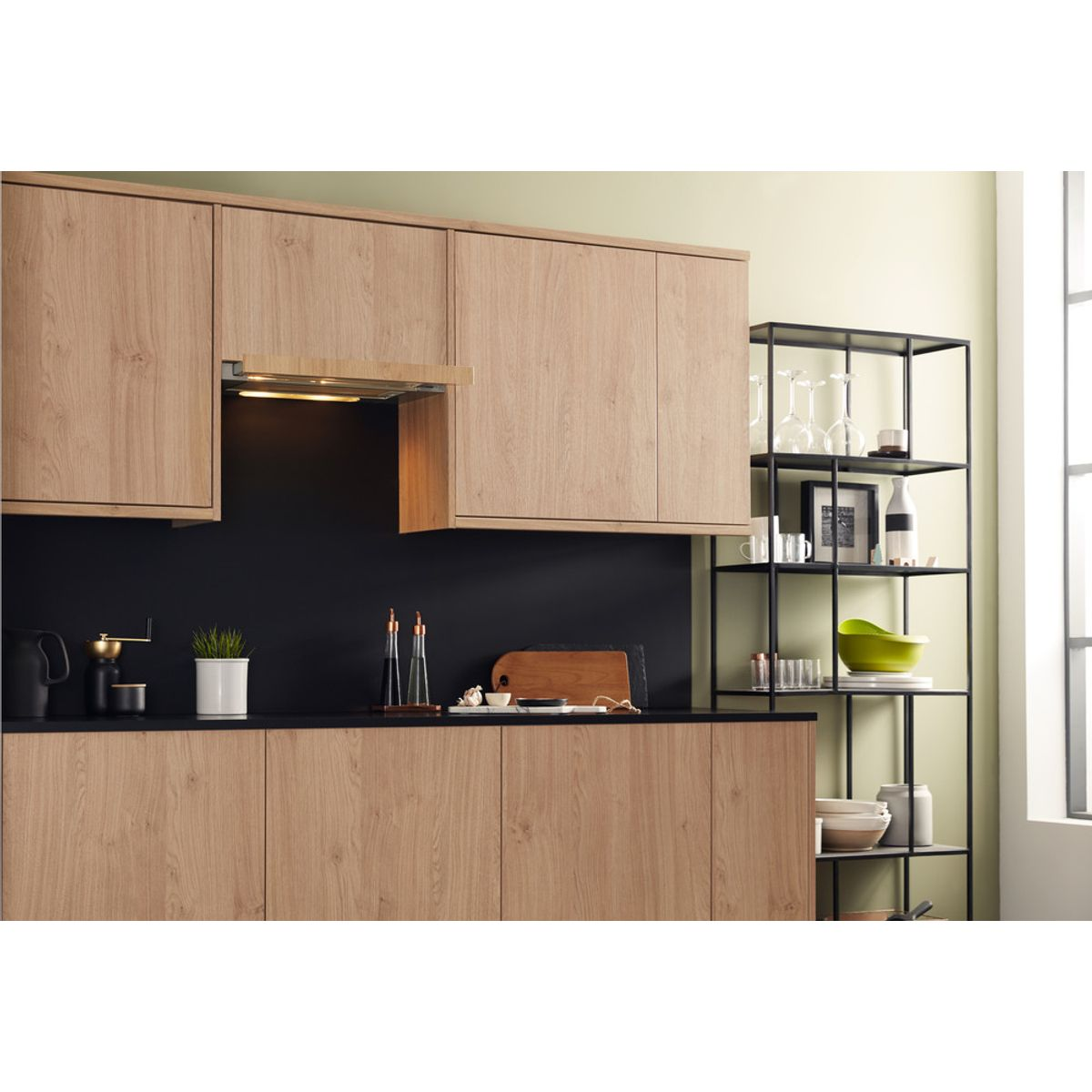 Cocina moderna con gabinetes de madera, salpicadero negro y estante negro con vasos.