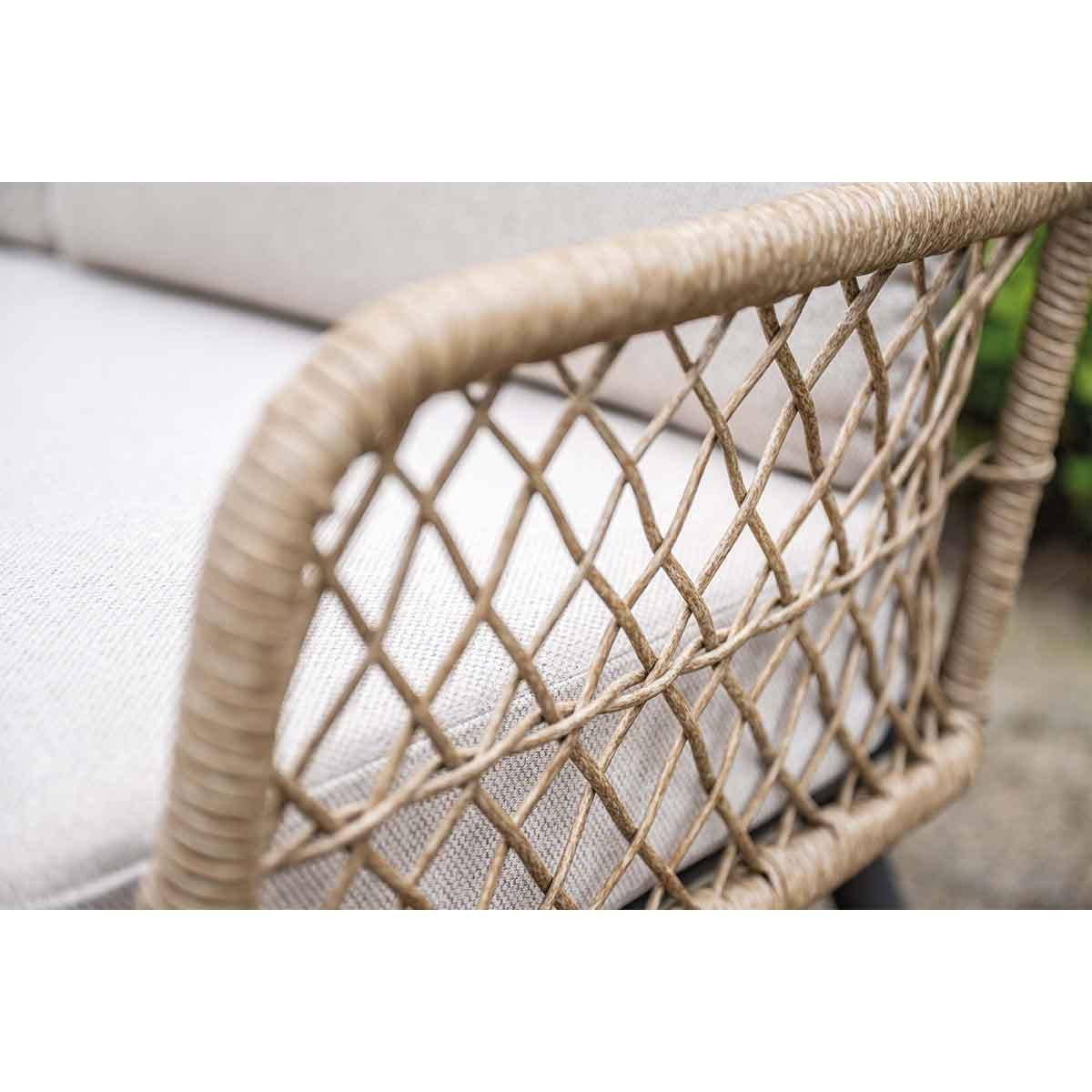 Chaise en osier avec coussin gris clair. Gros plan de l'accoudoir tressé.
