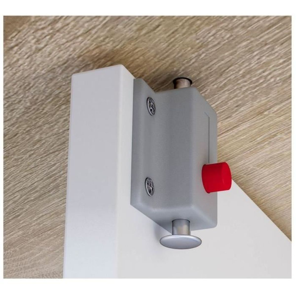 Cerradura gris con botón rojo en poste blanco, fondo de madera.