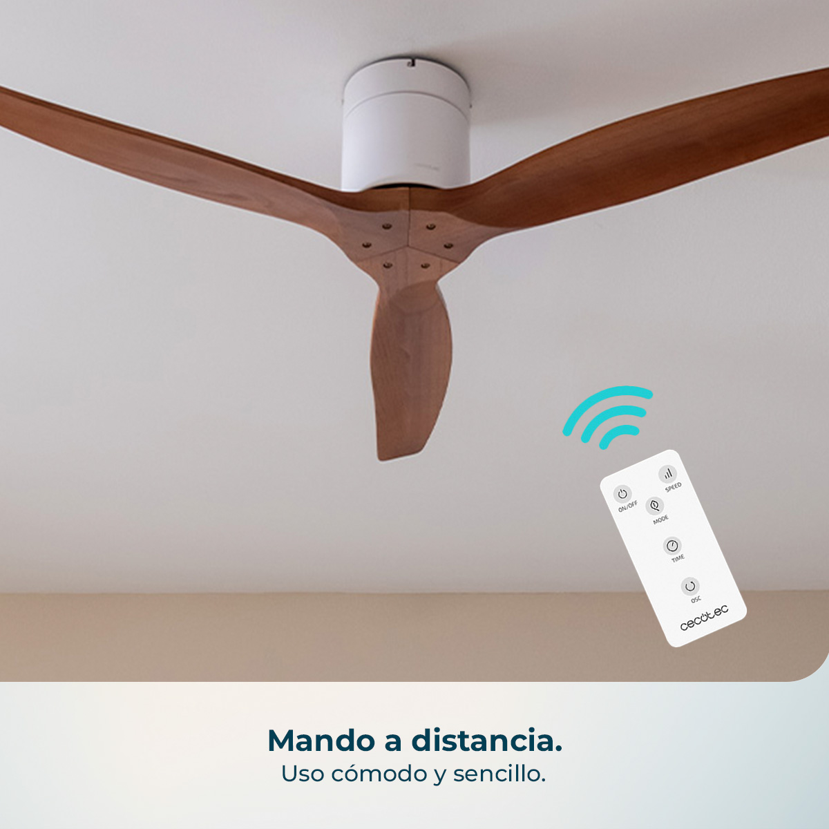 Un telecomando bianco con pulsanti giace vicino a un moderno ventilatore da soffitto in legno.