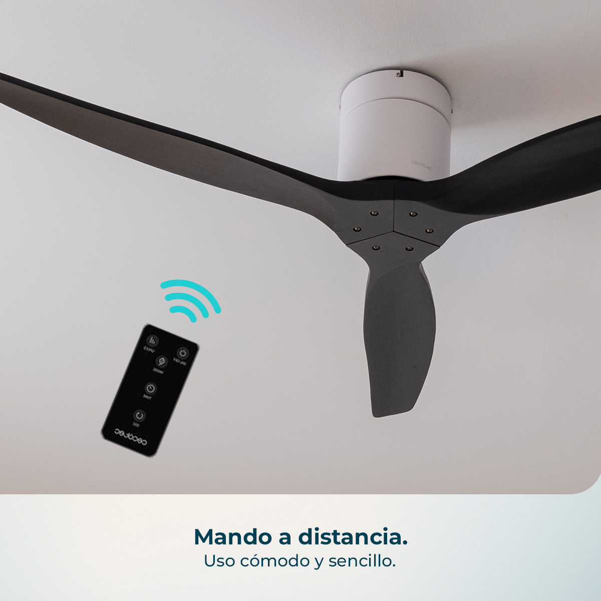 Un telecomando nero con icone fluttua sotto un ventilatore da soffitto scuro.