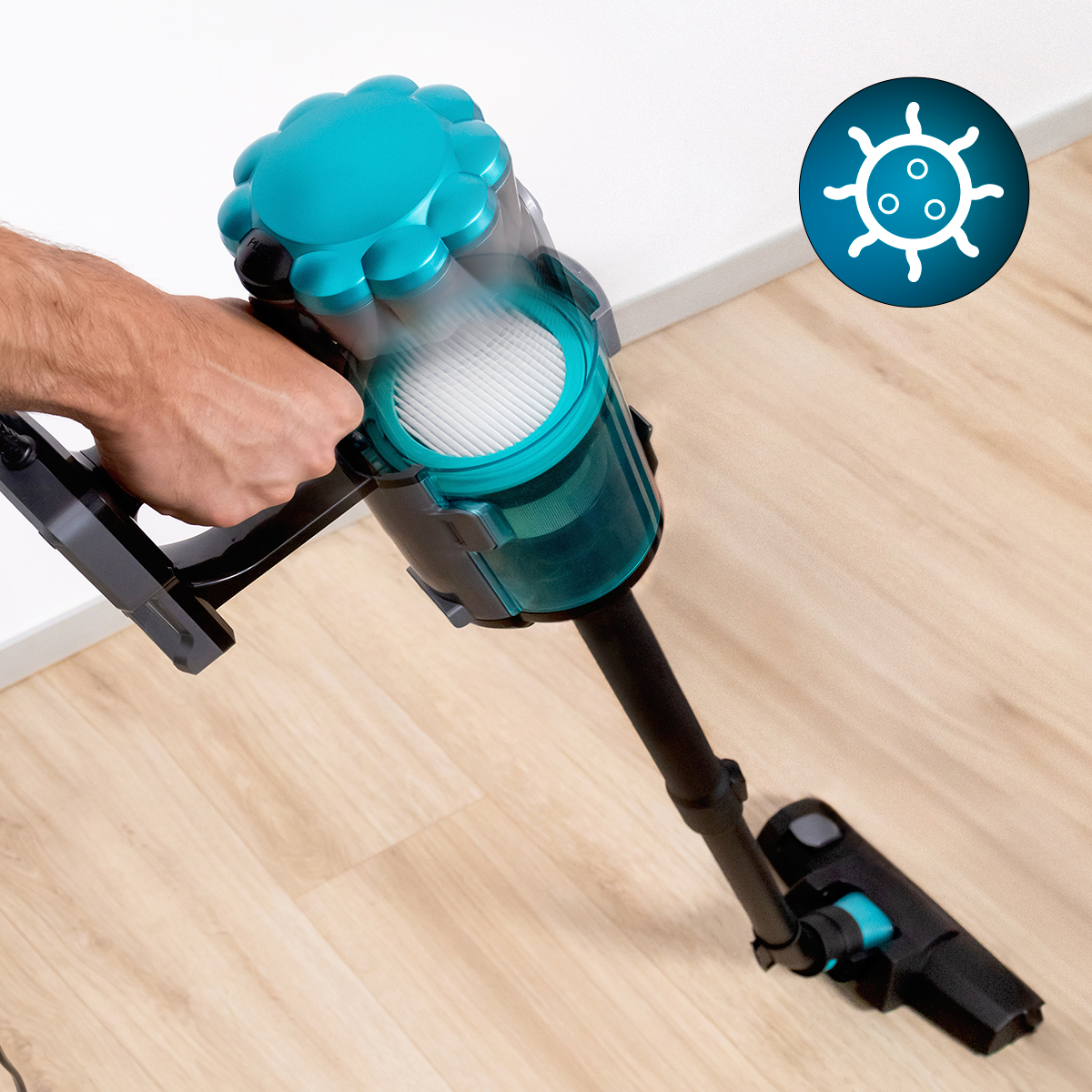 Odkurzacz ręczny czyści drewnianą podłogę. Widoczna ikona bakterii.