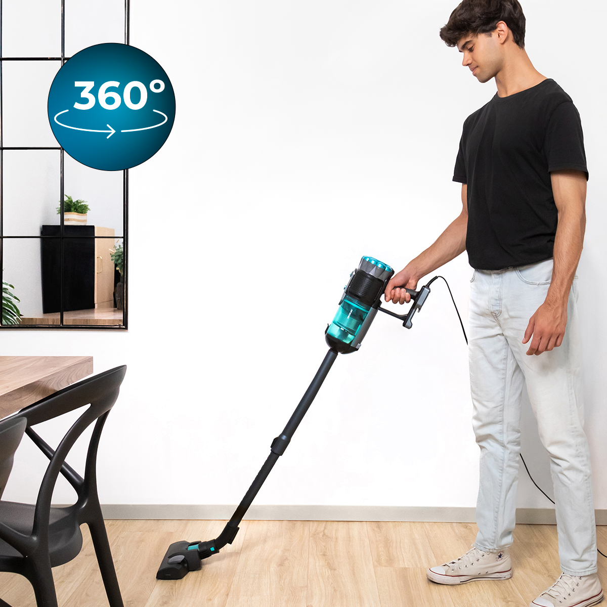 Mężczyzna w dżinsach i czarnej koszulce używa odkurzacza bezprzewodowego.
