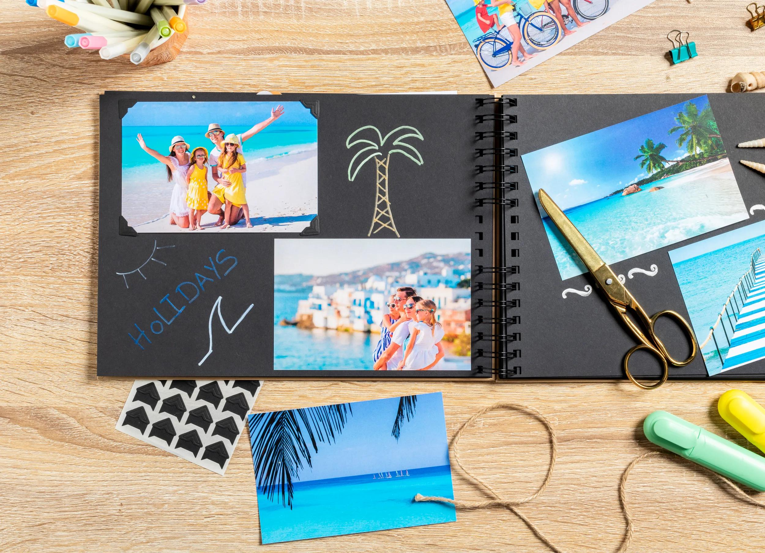 Un álbum de recortes abierto con fotos de vacaciones, bolígrafos, tijeras y cuerda.